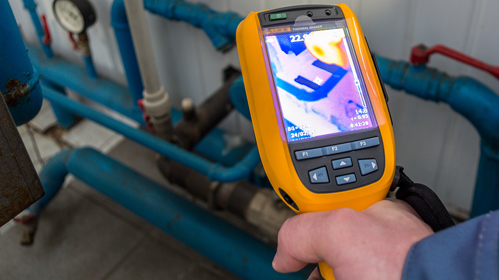 Heat leakage measurement in the plant, handheld meter in foreground in hand