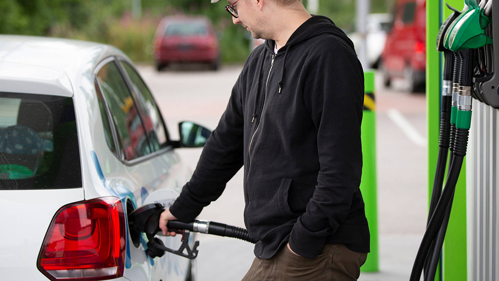 Mannen tankar bensin på en bensinstation i sin bils tank