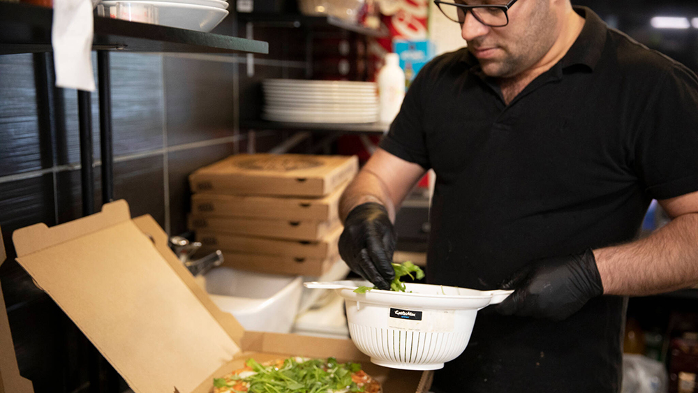 Kuvassa on kokki viimeistelemässä annosta ennen kuljetusta