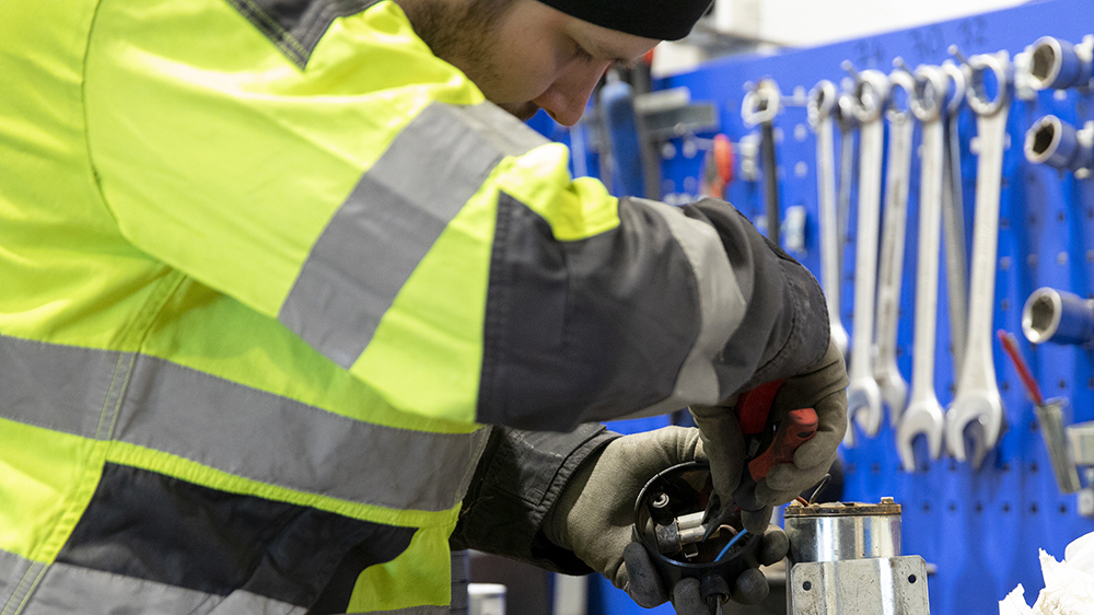 Kuvassa mies korjaustöissä. Ympärillä erilaisia työkaluja, kuten jakoavaimia.