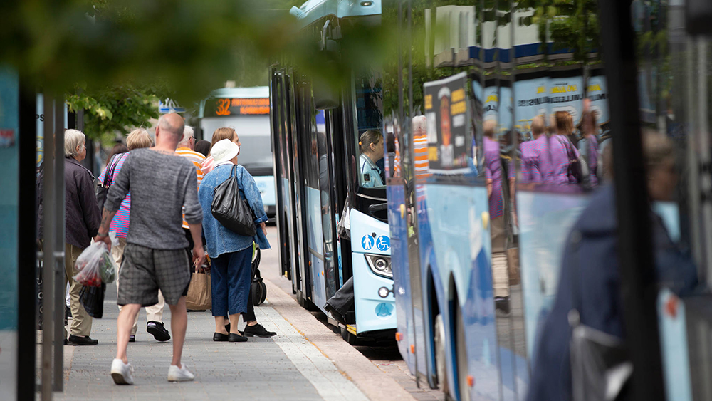Människor går ombord på en buss i staden.