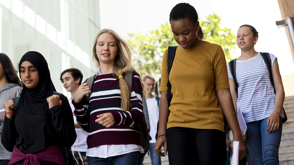 Kuvassa on joukko nuoria opiskelijoita kävelemässä yhdessä.