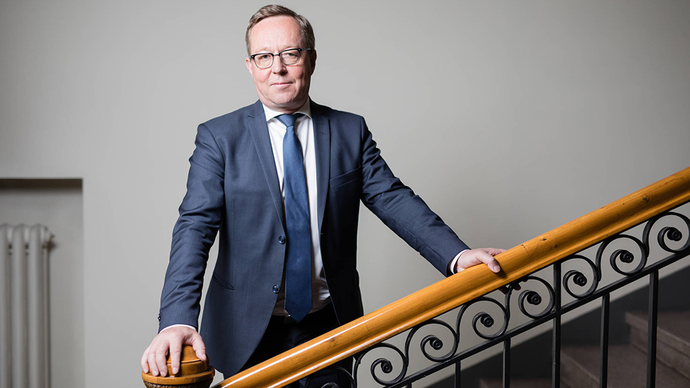 Elinkeinoministeri Mika Lintilä portaissa kaiteeseen nojaten