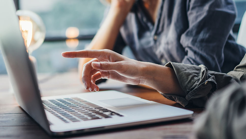 Käsi osoittaa läppäriä.