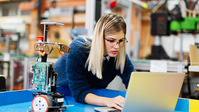 En ung kvinna arbetar i teknisk arbetsplats och see lap-top.