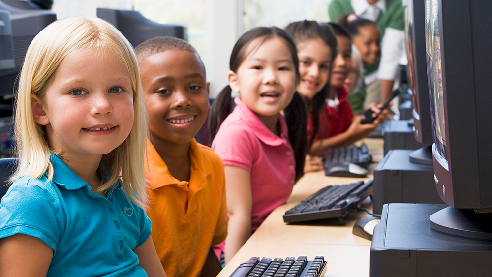 Barn i olika färg framför datorer.