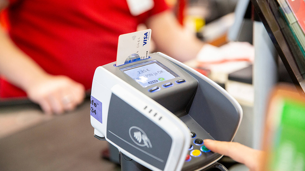Asiakas maksaa ostoksiaan kaupassa ja näppäilee pin-koodia kortinlukijaan.