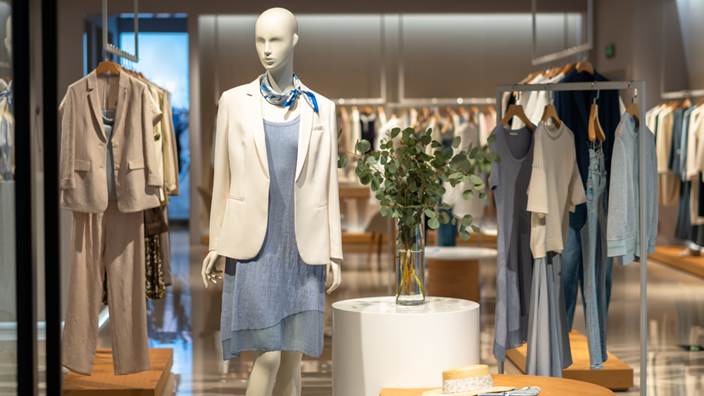 Kuvassa on etualalla mallinukke ja esillä on naisten vaatteita liikkeessä.