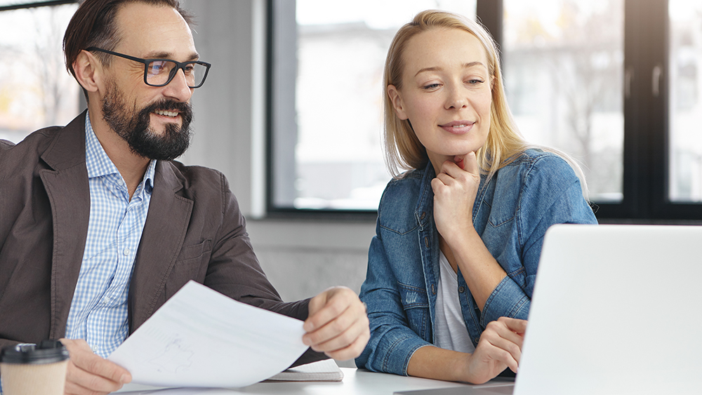 Työntekijäkaksikko pitää palaveria tietokoneen äärellä.