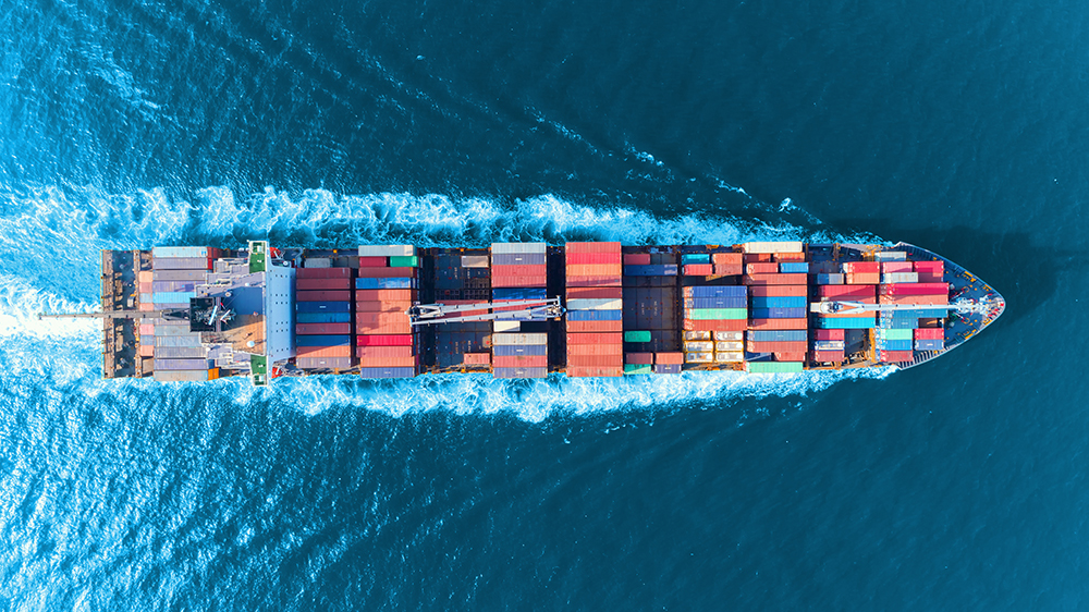 A cargo ship with containers in the open sea seen from above
