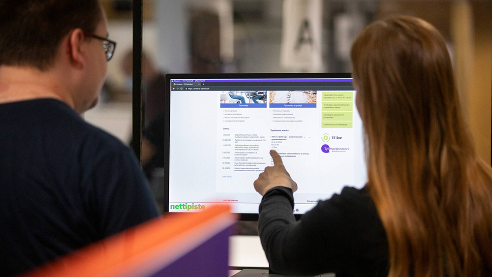 TE-toimiston työntekijä neuvoo asiakasta tietokoneen äärellä.